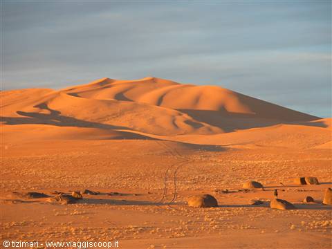 Golden sand dunes at dawn with scattered boulders in the desert