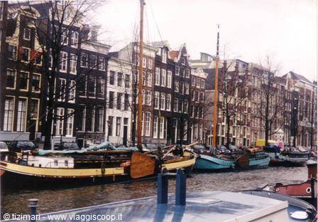 Narrow canal houses in Amsterdam, boats moored along the water