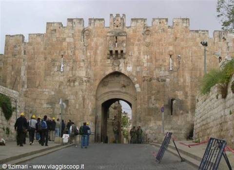 Tourists walk in front of Damascus Gate, ancient stone gate in Jerusalem