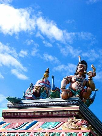 Painted Hindu deity statue atop a colorful temple roof