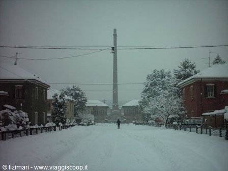 Person walks along snowy street in front of a tall monumental column