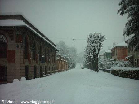 Snow-covered road between a brick arcade building and snow-laden villas