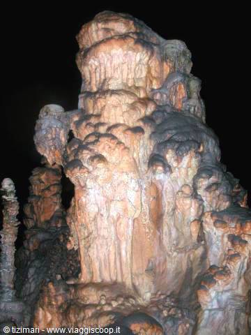 Limestone stalagmite formation illuminated inside a dark cave