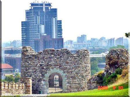 Stone tower with arched gate, modern skyscrapers of Belgrade behind