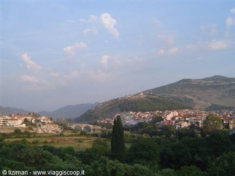 Trebinje: old stone bridge by the riverbank, red rooftops and green hill