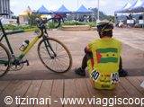 Cyclist in green jersey kneeling beside his racing bike on a wooden dock