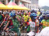 Cyclists in helmets under colorful tents, ready at the race start