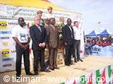 Cyclists' podium award ceremony with flowers and sponsor banners