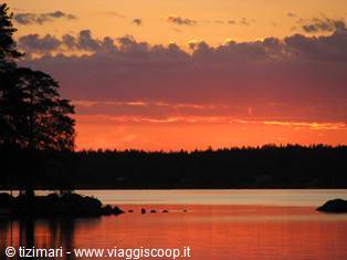 Red dawn over Swedish lake, trees and rocks in backlight