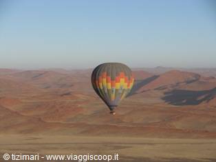 Colorful hot air balloon flying over the red dunes of the Namib desert