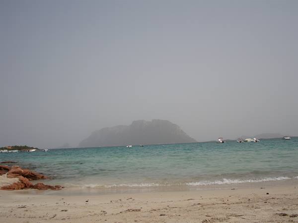 Pale sandy beach, turquoise water and hazy Tavolara island