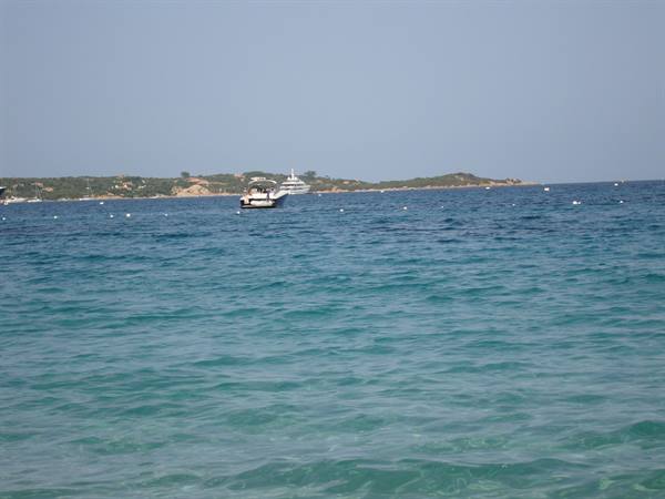 Turquoise sea with a small motorboat and green coastline in the background