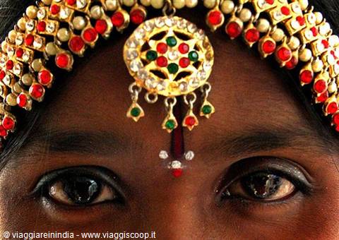 Woman's eyes with gold jeweled headpiece, red and green stones, bindi on forehead