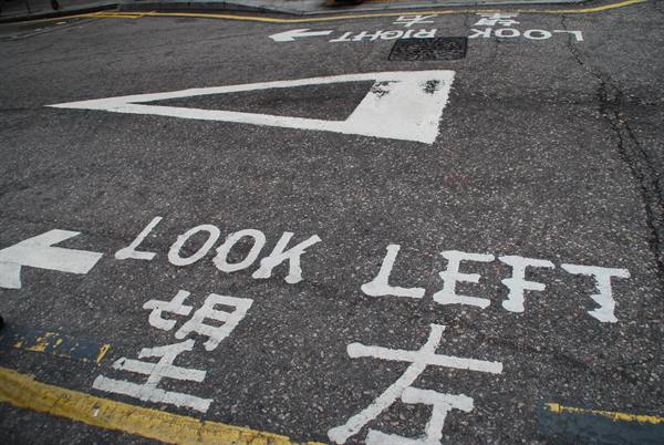 White Look Left markings and Chinese characters painted on wet asphalt road