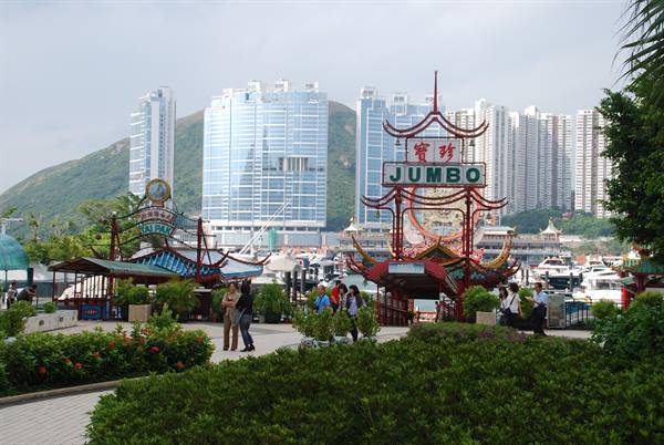 Jumbo sign on Aberdeen pier, tourists and skyscrapers behind the marina
