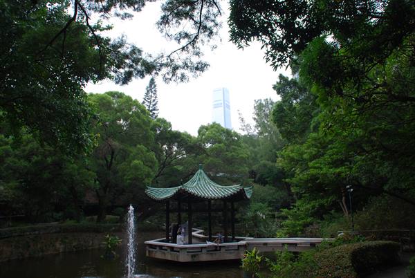Chinese pavilion on pond with fountain at Kowloon Park, among dense trees