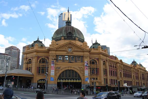 Flinders Street Station, facciata gialla con cupola verde sotto cielo nuvoloso