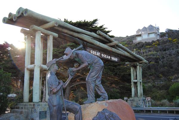 Sculture di bronzo di due uomini sotto il portale di tronchi della Great Ocean Road