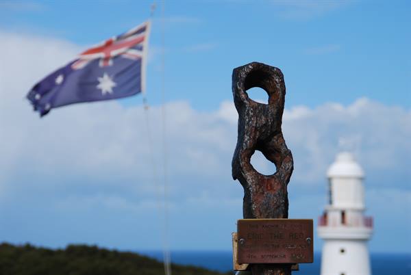 Memoriale con catena arrugginita al faro di Cape Otway, bandiera australiana al vento