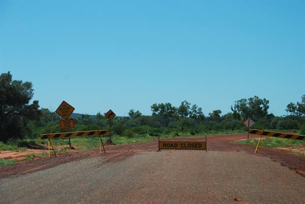 Strada sterrata chiusa da barriere gialle nel rosso outback