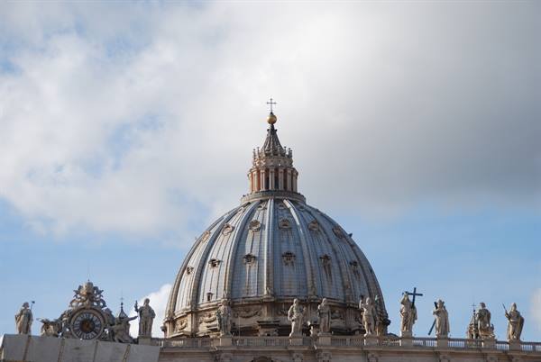 St. Peter's dome with statues under a cloudy sky, Vatican