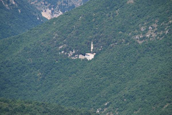 Sanctuary with slender bell tower hidden in the green mountain forest