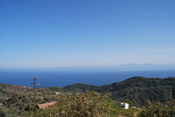 Green hills with white houses and power pole above the blue sea