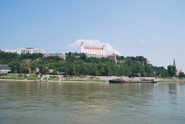 Bratislava Castle white on the hill above the Danube, barge on river