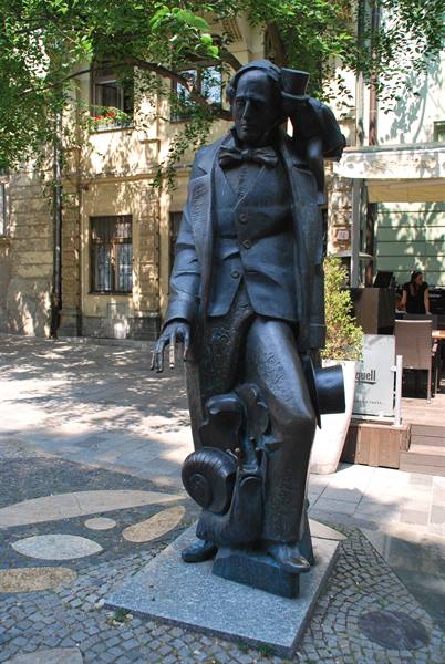 Bronze statue of a man with top hat and violin on cobbled street