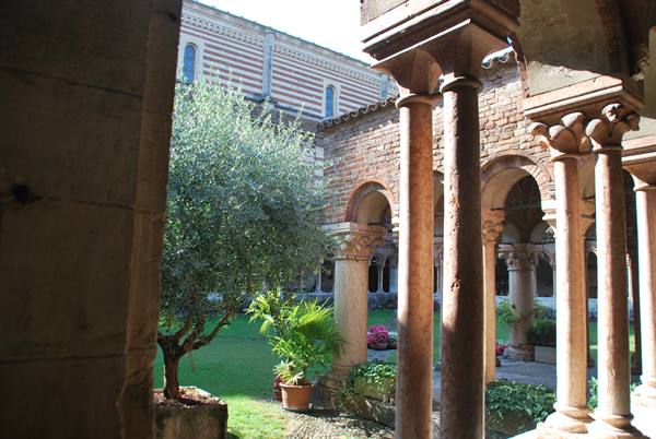San Zeno cloister in Verona, marble columns among greenery and sunlight