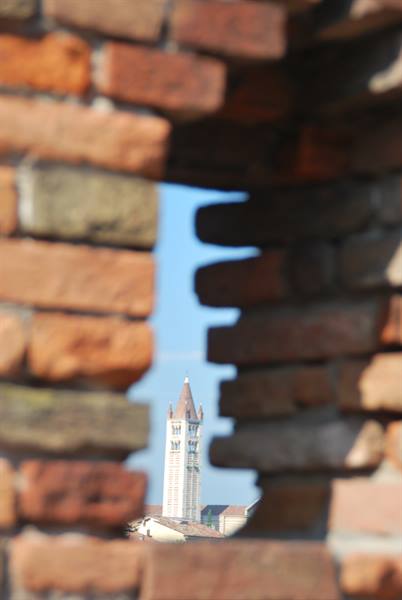 Brick bell tower framed through an opening in a red brick wall