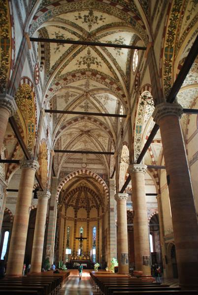 Inside Verona's Basilica of Santa Anastasia: frescoed vaults, stone columns, visitors among the pews