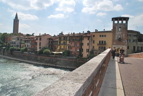 Tourists with stroller on the brick bridge over the Adige in Verona