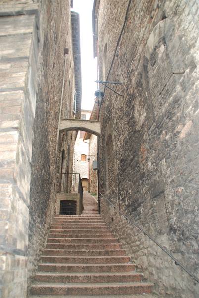 Stone staircase between medieval walls, with an arch and a lantern