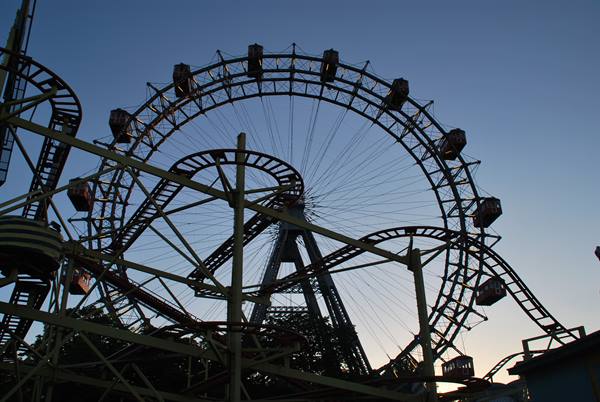 The Riesenrad Ferris wheel in Vienna's Prater backlit among roller coasters