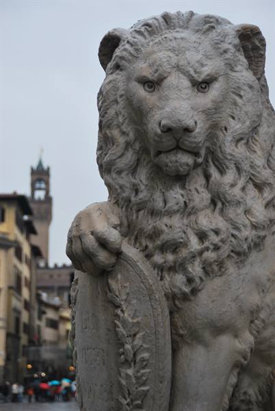 Marble lion statue holding a shield in Florence's Piazza della Signoria under grey light