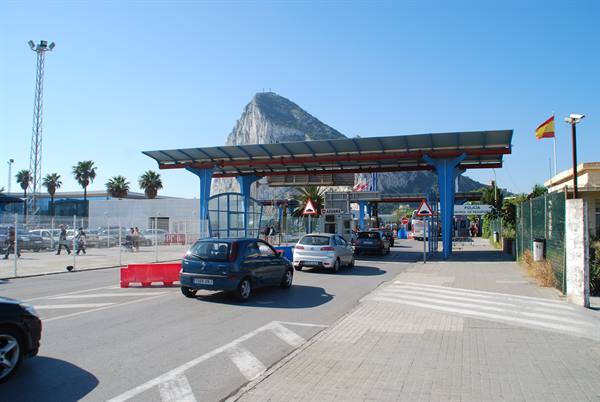 Cars at the Gibraltar border crossing, the Rock towering under blue sky