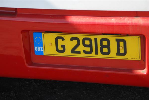 Yellow GBZ license plate G 2918 D on a red bus in sunlight