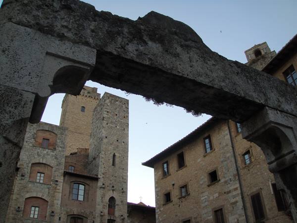 Medieval towers of San Gimignano framed by a weathered stone arch