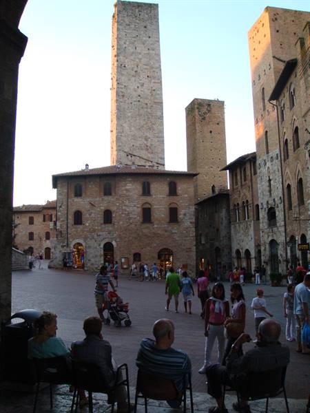 Tourists sitting in the square among San Gimignano's medieval towers