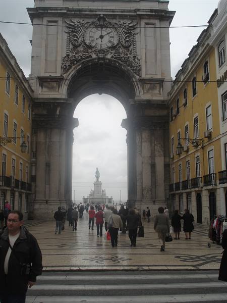 Pedestrians walk under the Rua Augusta Arch toward the square, Lisbon