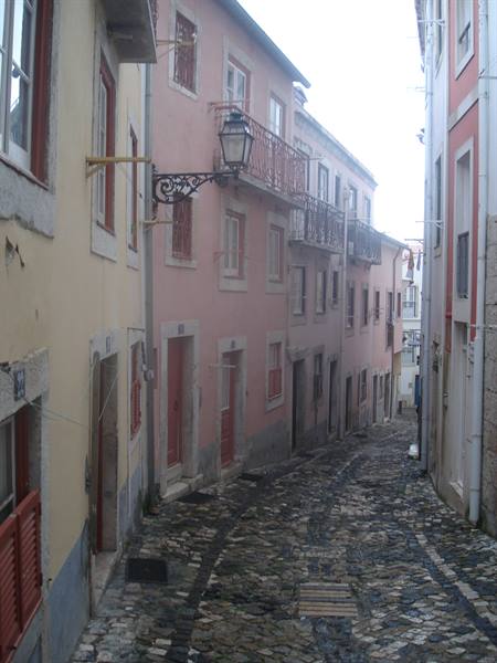 Steep cobbled street with pink houses and wrought-iron lantern, Lisbon