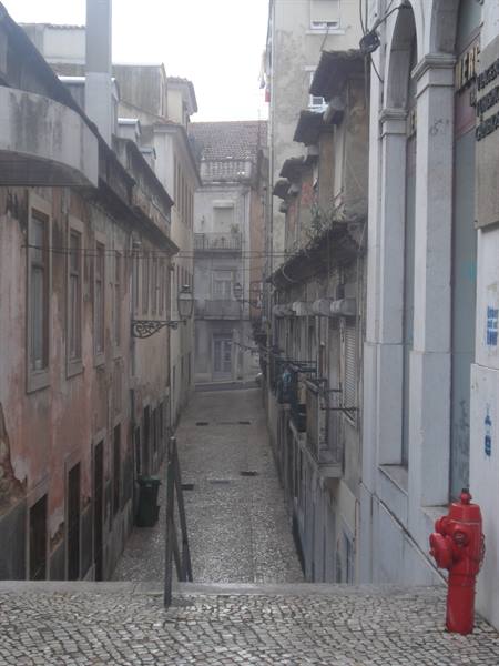 Steep alley with old buildings and red fire hydrant, grey light