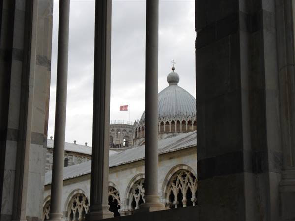 Marble columns frame Pisa Cathedral dome under a grey sky