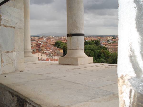 White marble column on terrace, Pisa rooftops under cloudy sky