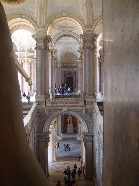 Grand staircase of Caserta Royal Palace, visitors beneath marble arches