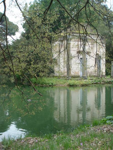 Classical stone temple by the pond, reflected among overhanging branches