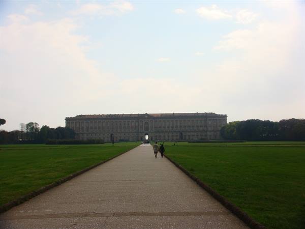 Straight avenue toward the Royal Palace of Caserta, green lawns and few walkers
