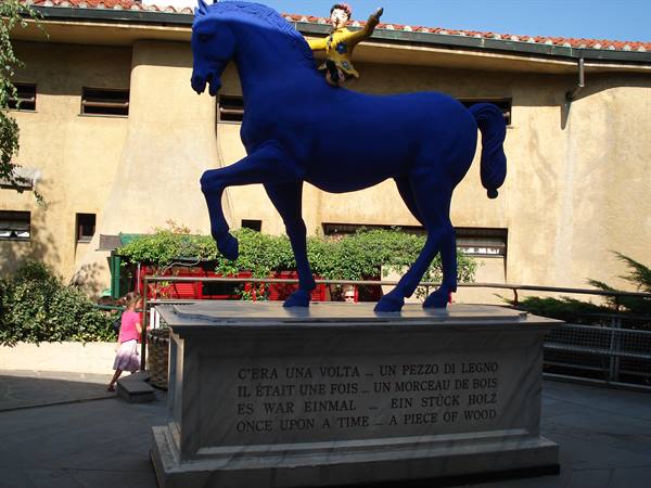 Blue horse statue with Pinocchio on marble pedestal at Collodi