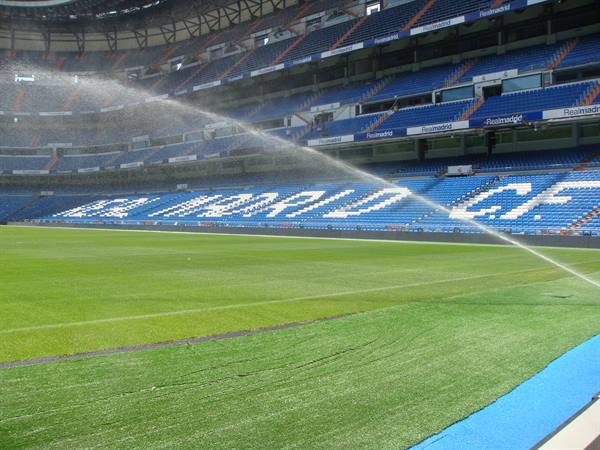 Sprinklers watering the pitch at Santiago Bernabéu stadium, Real Madrid blue stands